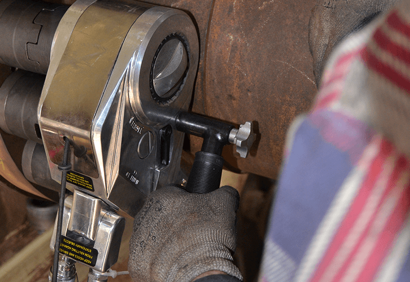 Technician operating HYTORC Avanti hydraulic torque wrench on large industrial bolts